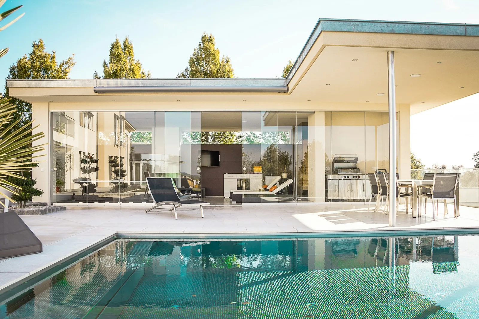 Illustrative photograph of a home opening onto a patio and swimming pool
