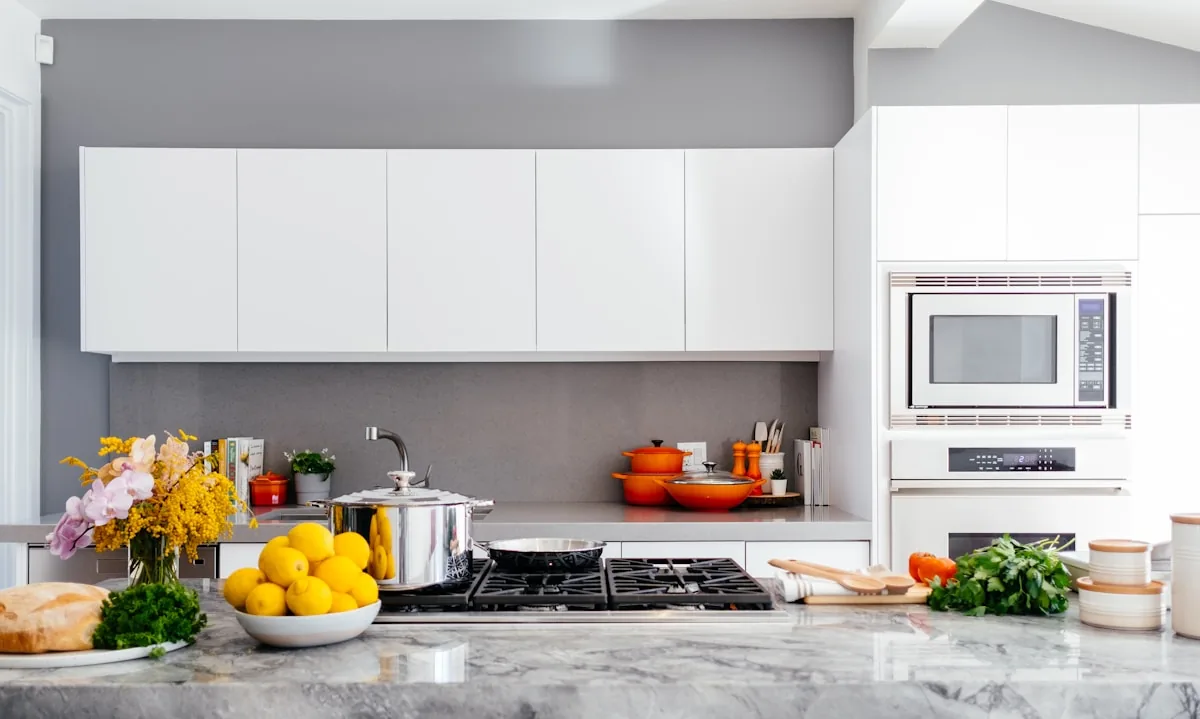 Illustrative photograph of a kitchen with white cabinetry and a stone worktop